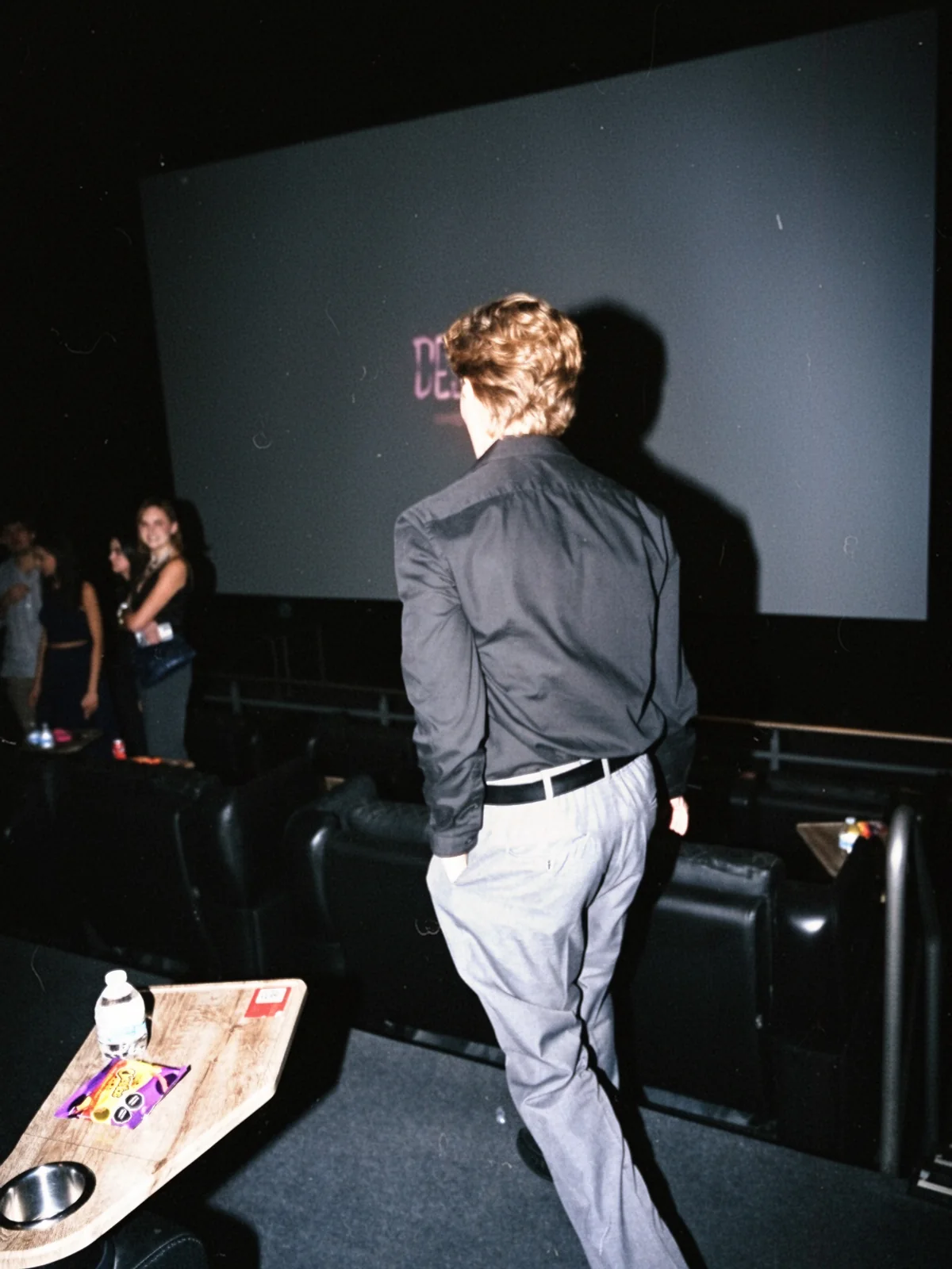Andre de espaldas camina por la sala de cine hacia la pantalla.