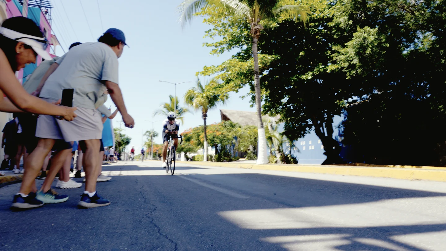 Espectadores se acercan al paso de un ciclista en la calle.
