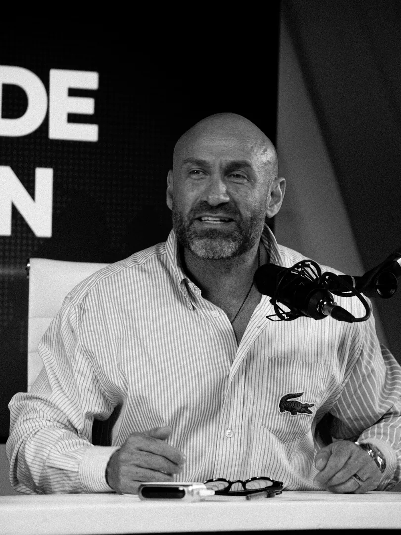 Pedro Ferriz sonríe en el set frente a dos micrófonos.