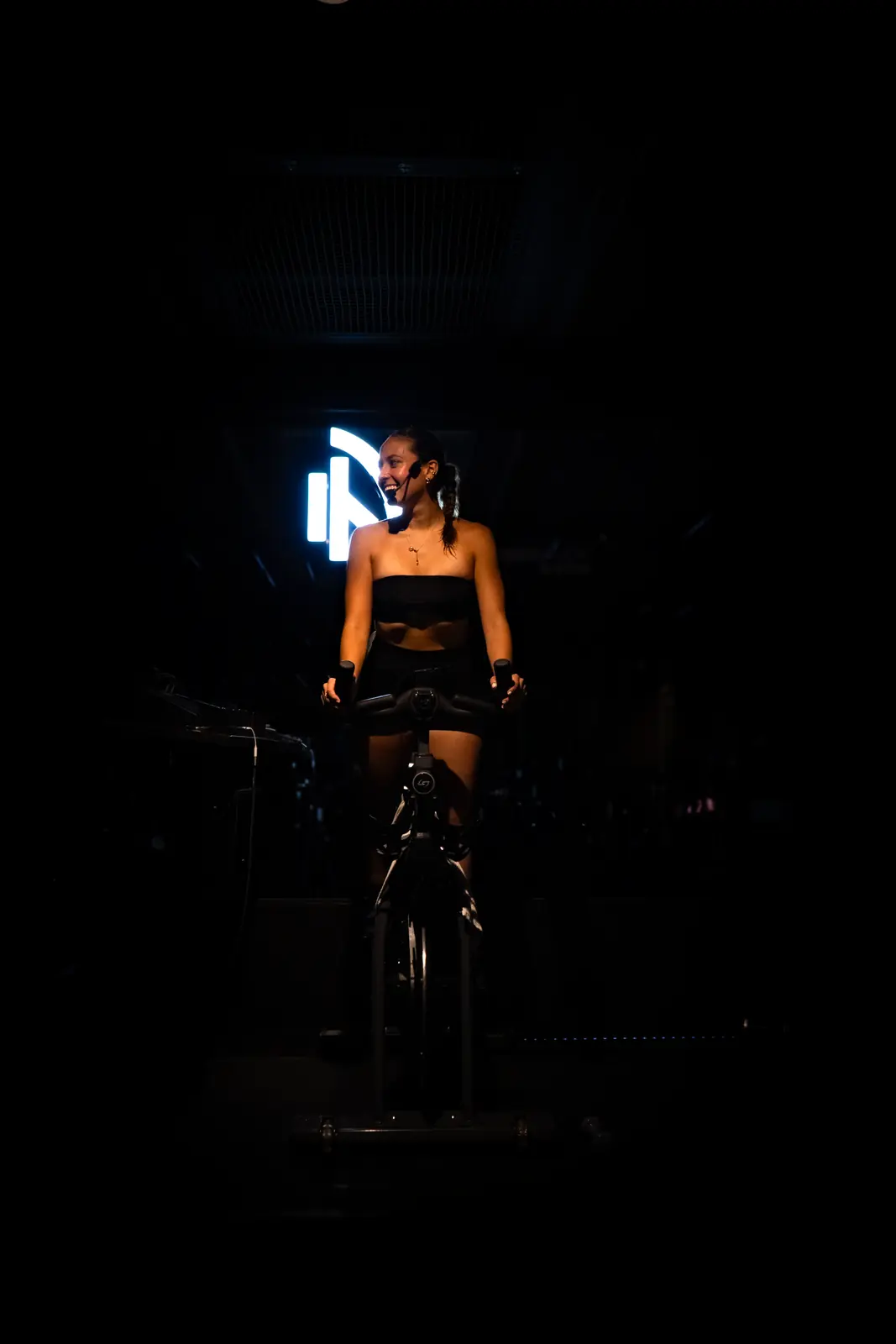Mia Malacara guía la clase desde la bicicleta bajo luz puntual.