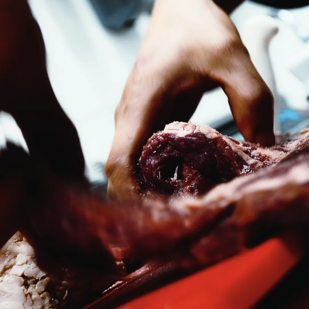 Manos preparan un corte de carne cruda en la mesa de trabajo.
