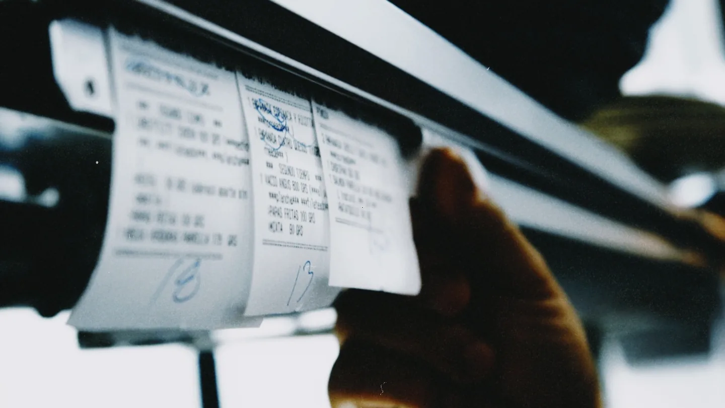Mano toma un ticket de la rueda de comandas de la cocina.